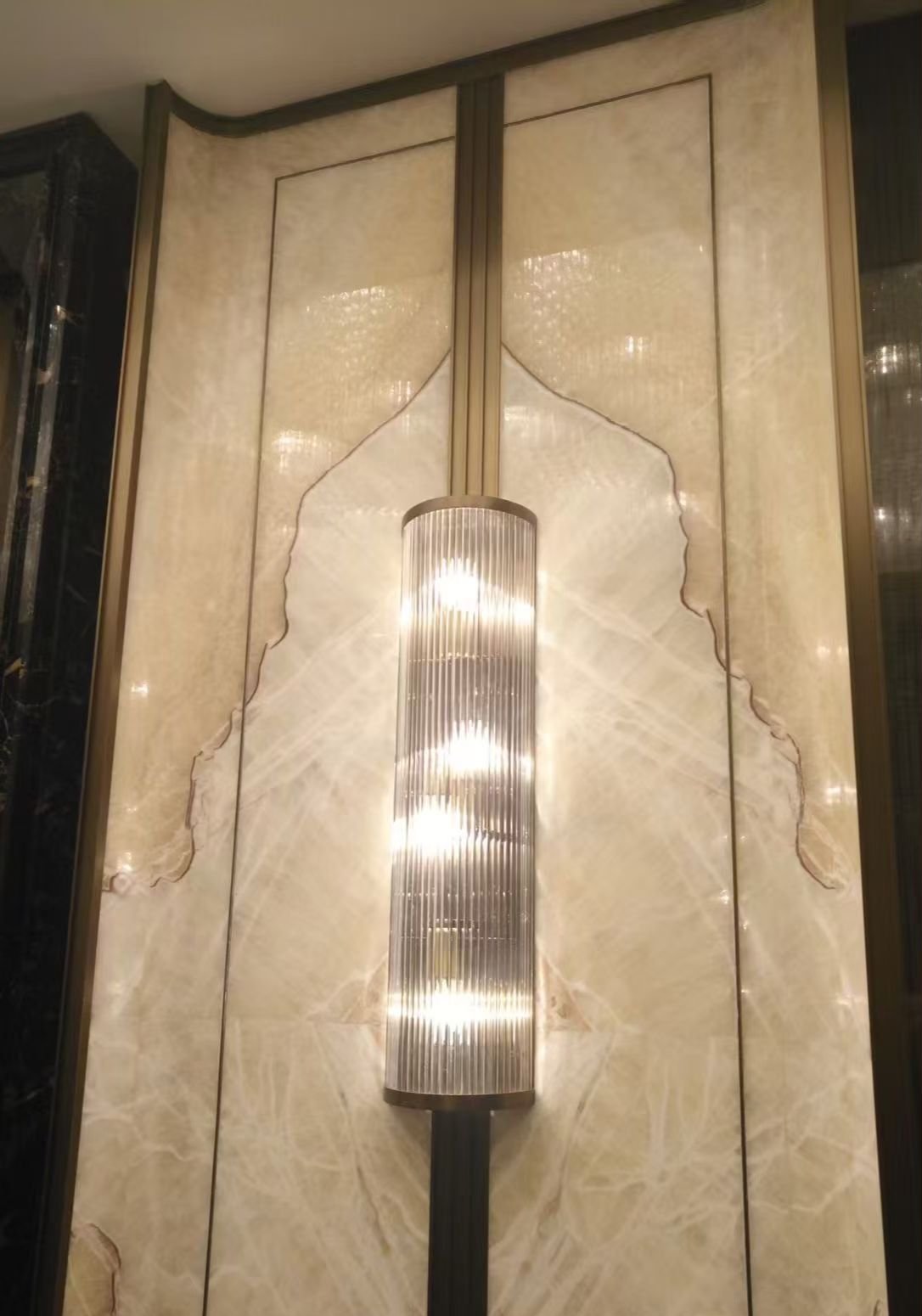Fluted glass sconce on backlit alabaster wall